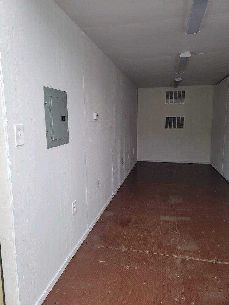 Custom 20 foot full-side-access conex container with an HVAC unit, interior framed insulated plywood walls, side bifold doors, and fully operational end doors (interior)